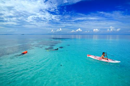 Snorkeler and Kayaking above the pristine waters of Yeben shallow, Raja Ampat